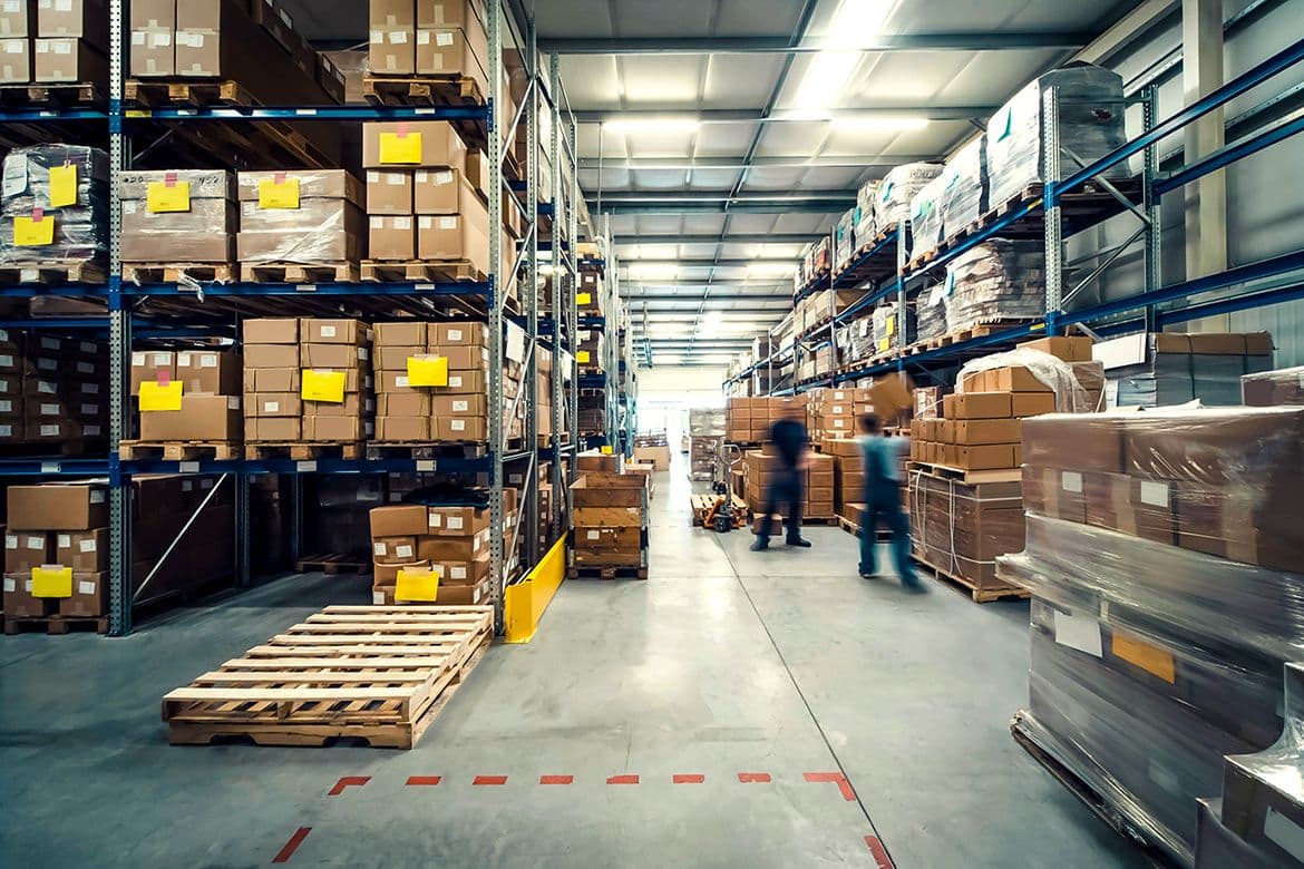 Warehouse aisle with shelved inventory, showing the stock an ecommerce inventory management system consultant helps you track.